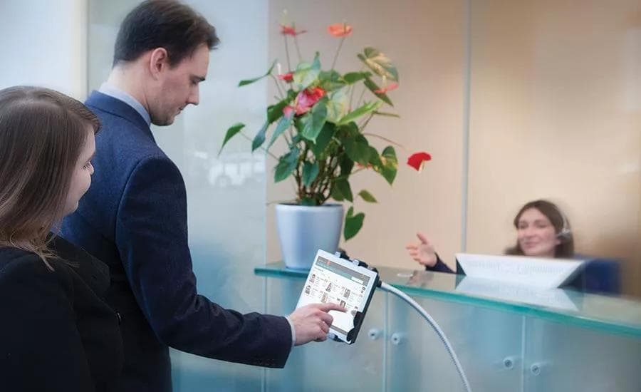 Visitors registering on a check-in tablet at a corporate reception